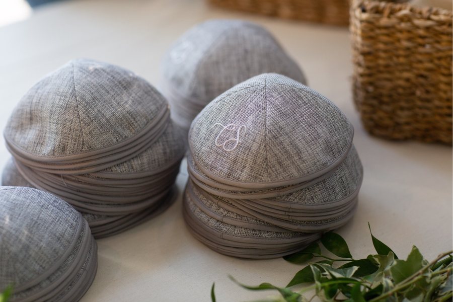 Kippas personnalisées en lin gris avec monogramme brodé blanc, présentées en pile pour un mariage ou une cérémonie élégante.