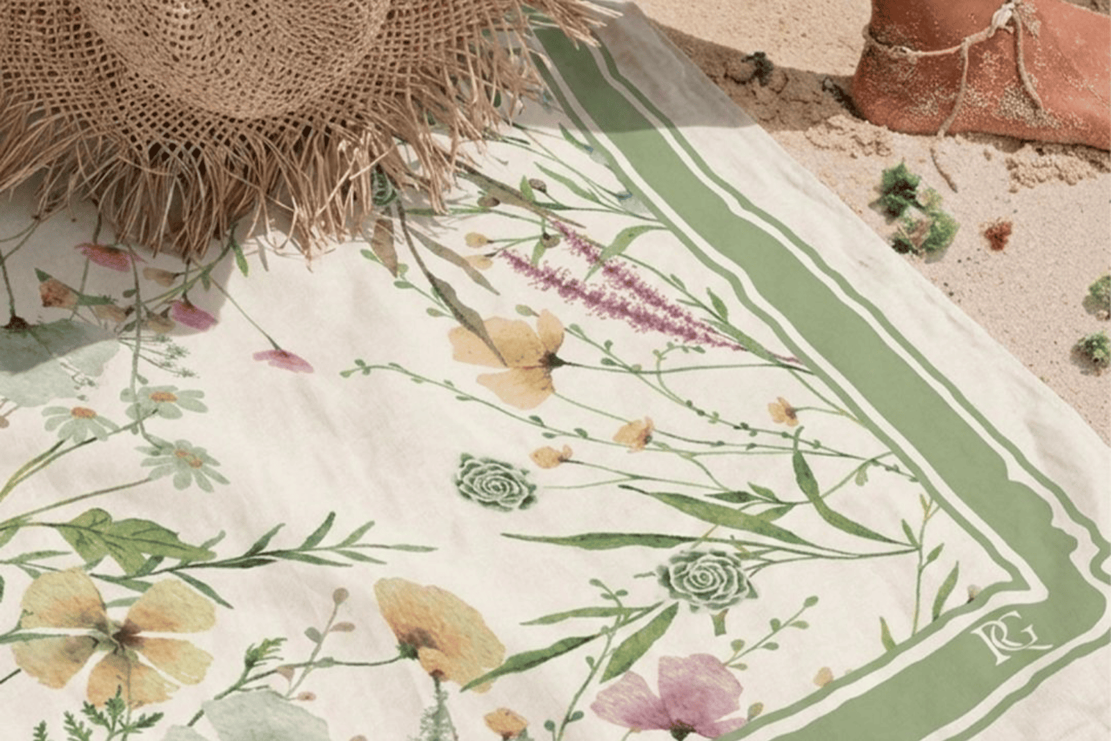 Fouta personnalisée à motif floral vert et pastel présentée sur une plage, idéale comme cadeau invité d'été.