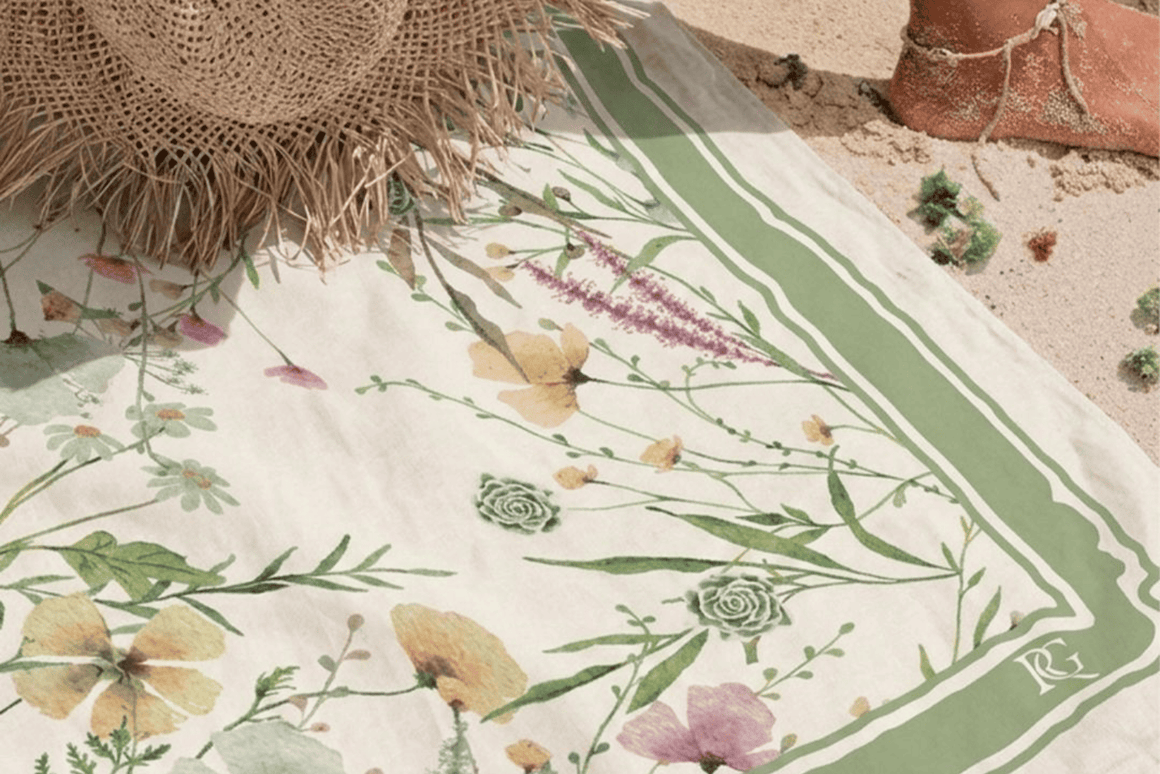 Fouta personnalisée à motif floral vert et pastel présentée sur une plage, idéale comme cadeau invité d'été.