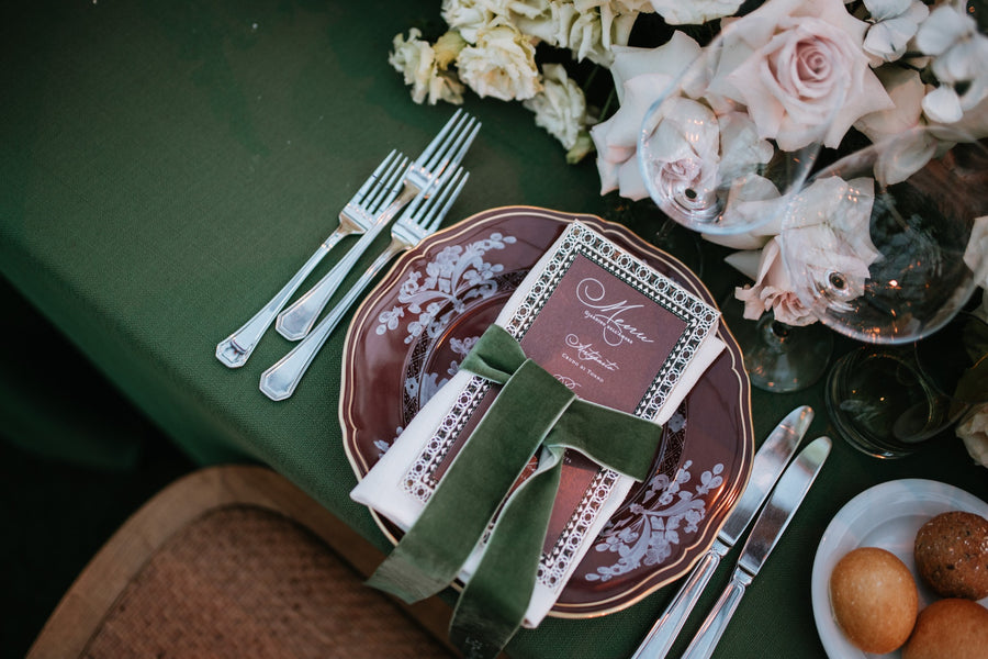 Menu de mariage personnalisé bordeaux avec ruban de velours vert sur une table de mariage