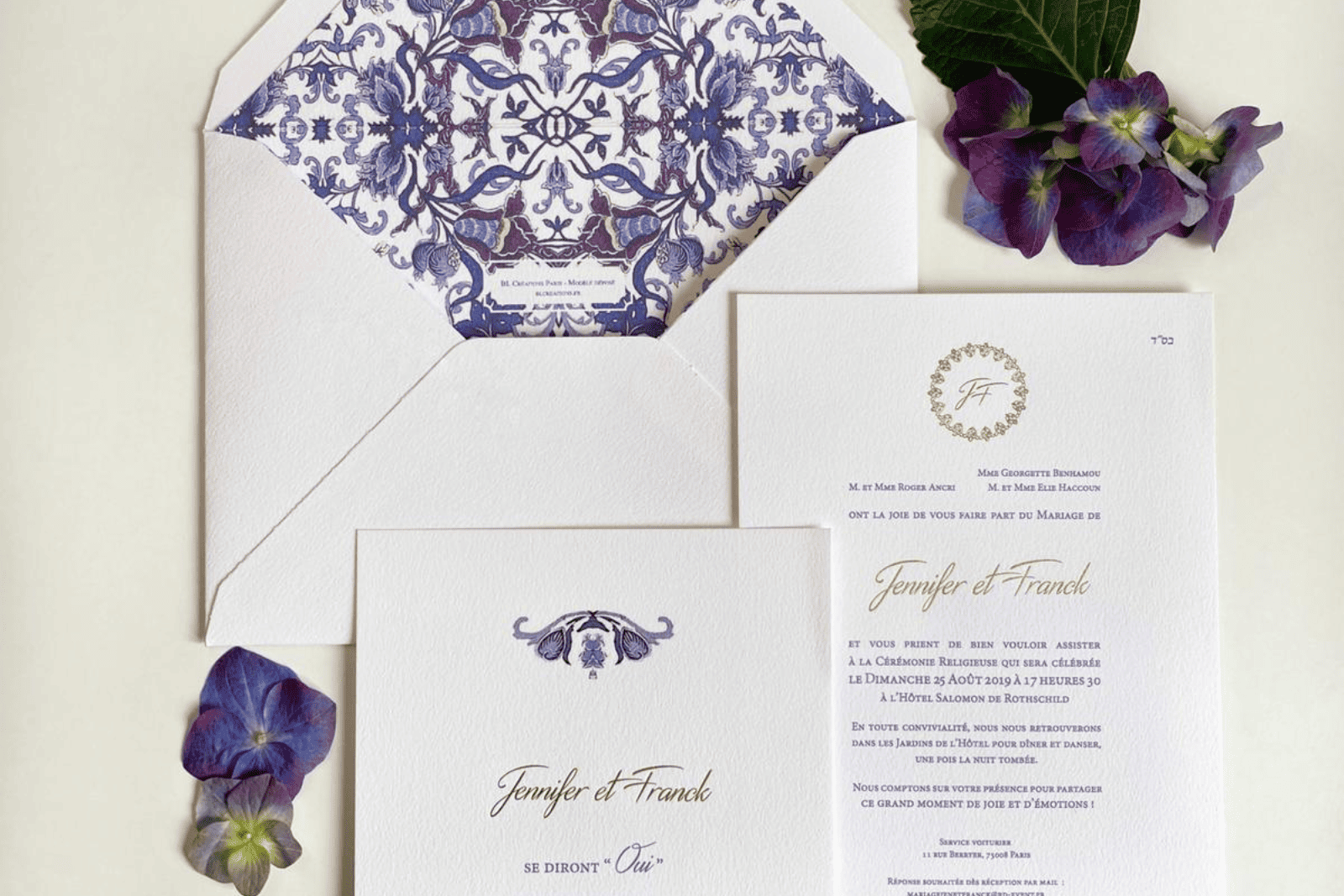 Faire-part de mariage haut de gamme signé BL Creations, imprimé sur papier texturé blanc avec détails bleu et or. L'ensemble comprend une invitation élégante, une carte de cérémonie et une enveloppe doublée d'un motif baroque bleu raffiné, présenté avec des fleurs d'hortensia violettes pour une mise en scène chic et intemporelle.