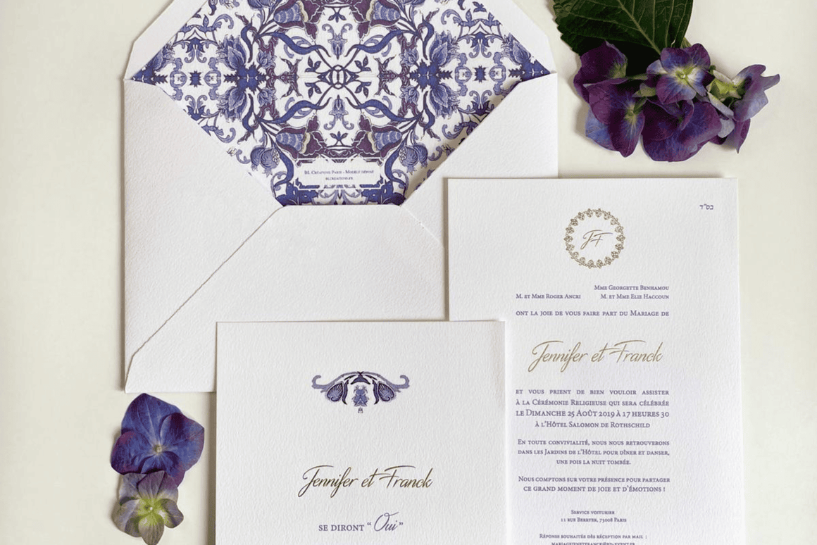 Faire-part de mariage haut de gamme signé BL Creations, imprimé sur papier texturé blanc avec détails bleu et or. L'ensemble comprend une invitation élégante, une carte de cérémonie et une enveloppe doublée d'un motif baroque bleu raffiné, présenté avec des fleurs d'hortensia violettes pour une mise en scène chic et intemporelle.
